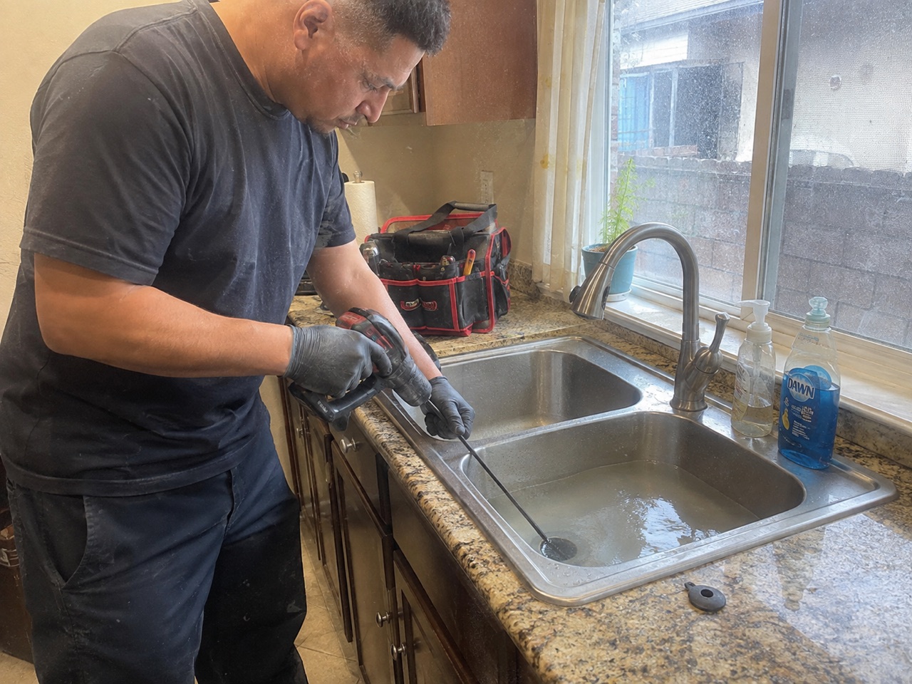 Technician cleaning a clogged kitchen sink drain in Stockton, CA
